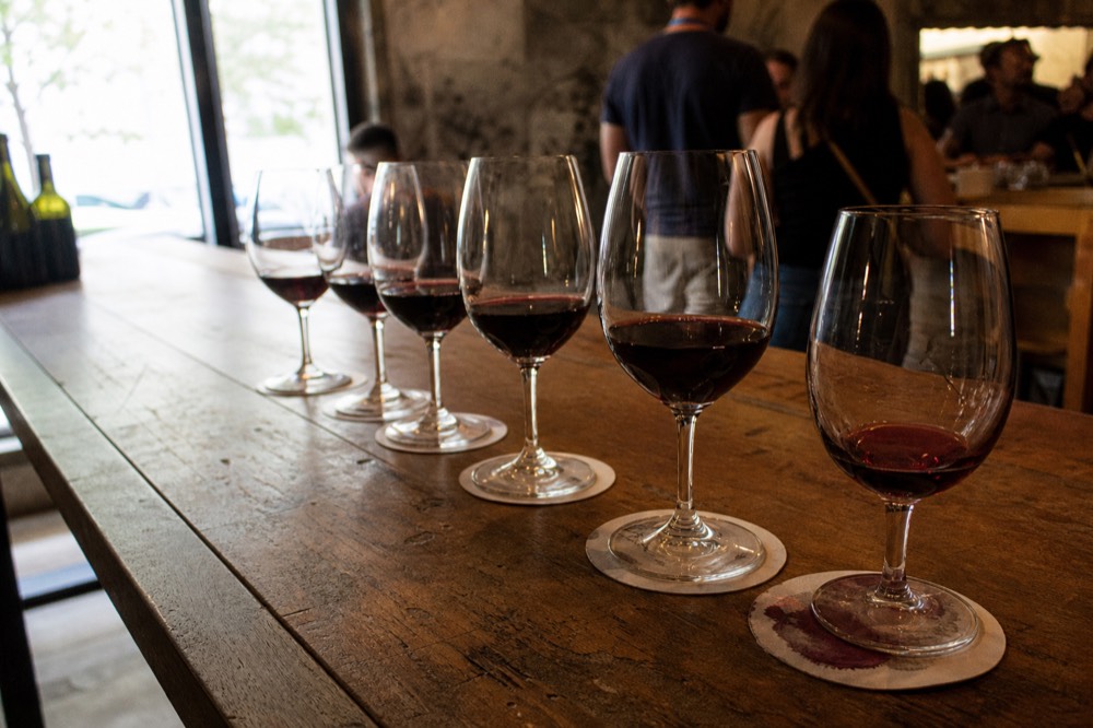 A tasting flight of red wines in glasses on a wooden counter, no text, no logos, no people