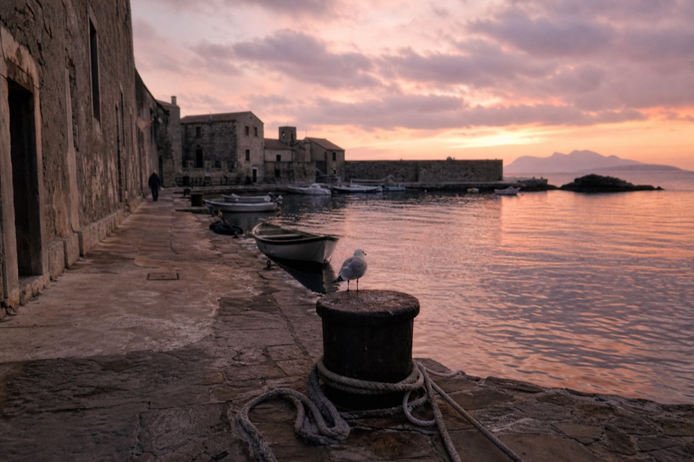 Historic lakeside town with stone buildings and moored boats, no text, no logos, no people