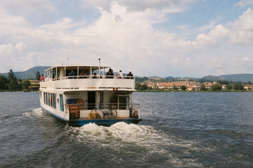 Passenger ferry crossing Lake Garda near a lakeside town, no text, no logos, no people