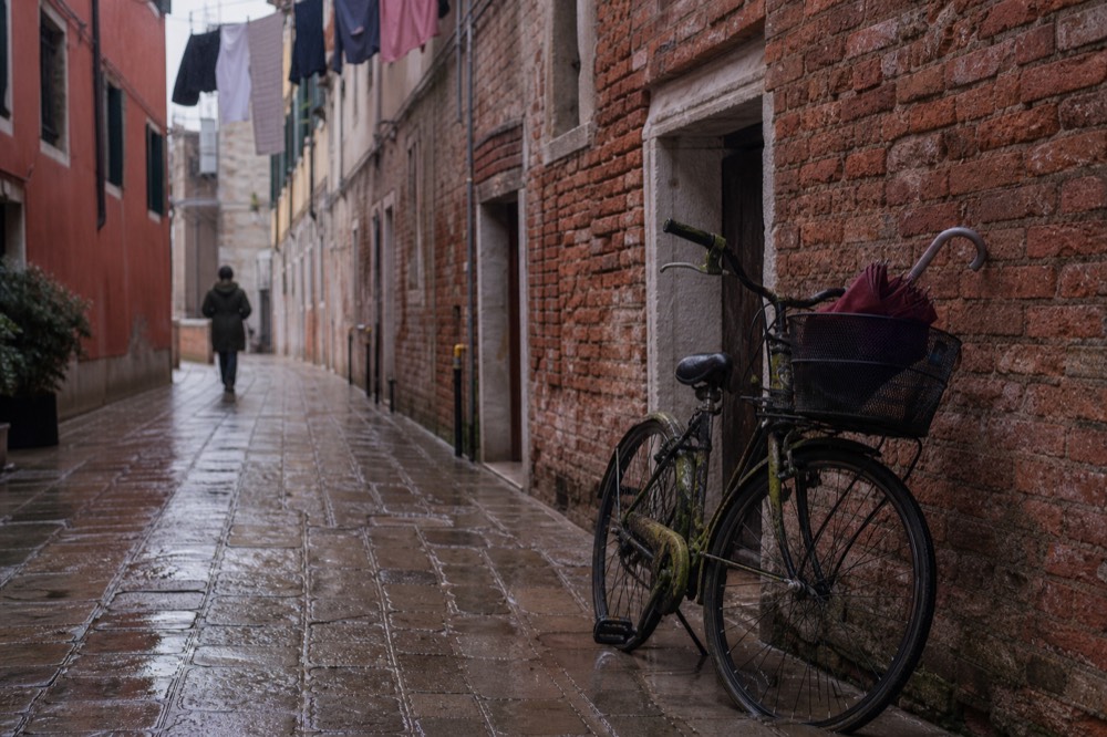 Narrow cobbled Verona street with old brick walls and hanging laundry, no text, no logos, no people
