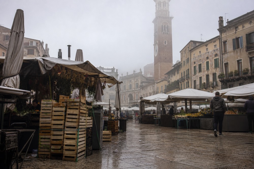 Piazza delle Erbe with market stalls and the Torre dei Lamberti in the background, no text, no logos, no people