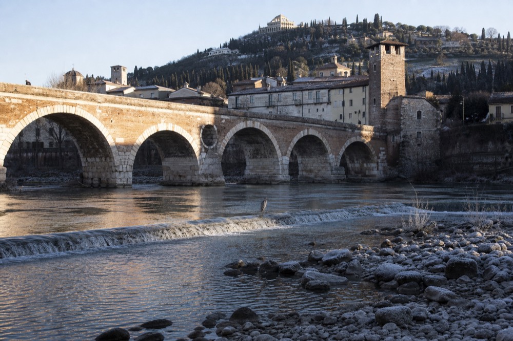 The Adige River and Ponte Pietra on a clear morning, with the Verona hills in the background, no text, no logos, no people