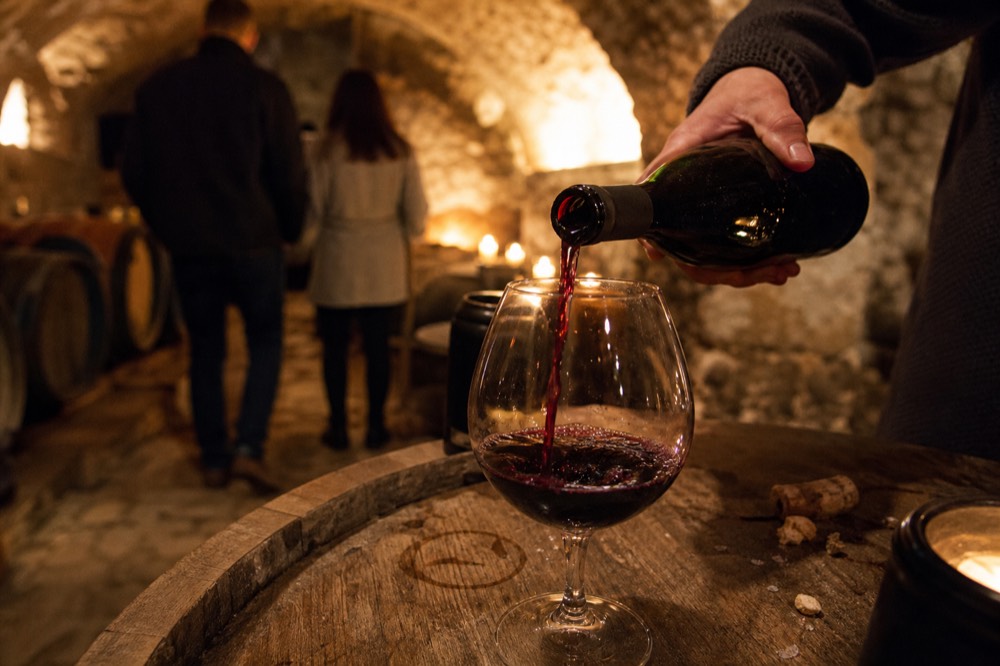 A sommelier pouring a glass of dark red Amarone in a cellar, no text, no logos, no people