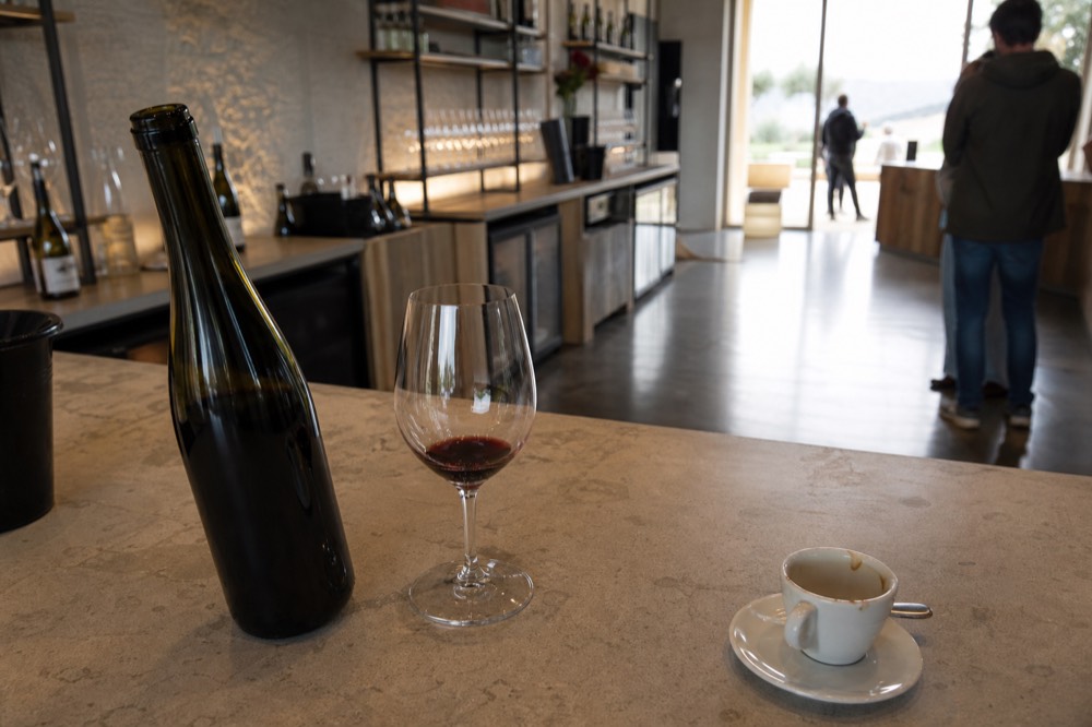 A glass of Ripasso red beside an open bottle on a wooden counter, no text, no logos, no people