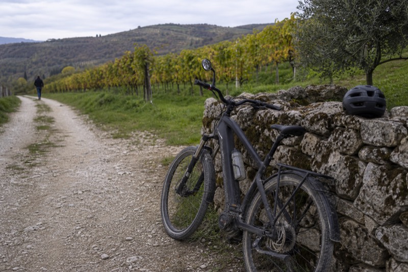 E-bike leaning on a dry-stone wall beside a Valpolicella vineyard lane