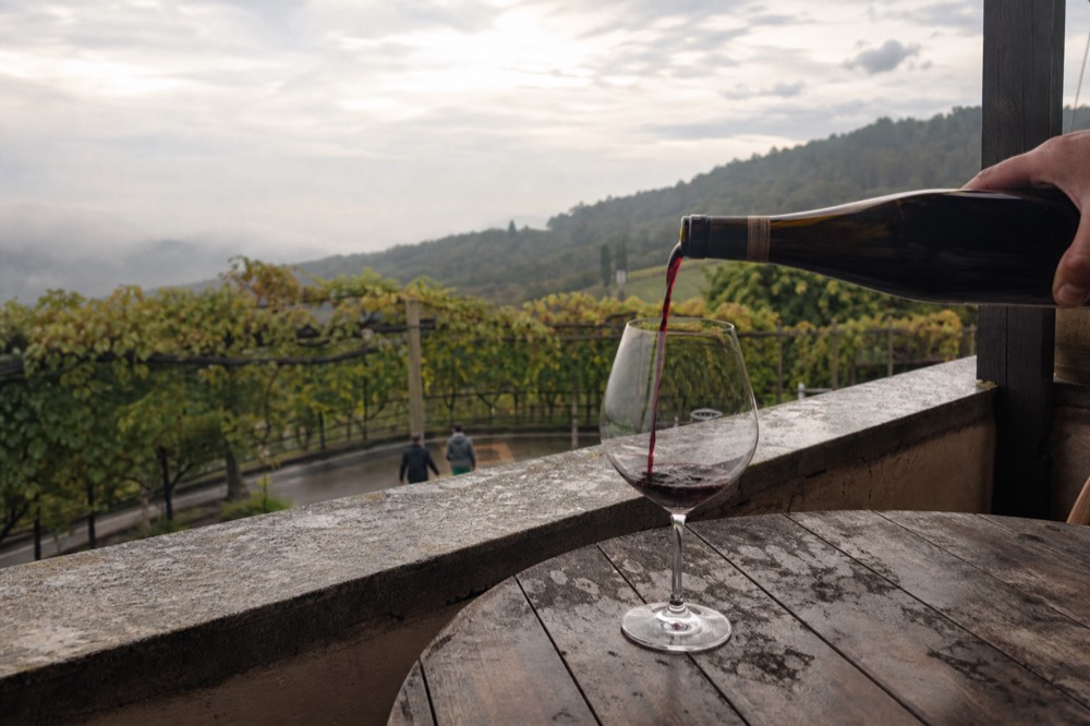 Amarone wine being poured into a glass against a Valpolicella hillside, no text, no logos, no people