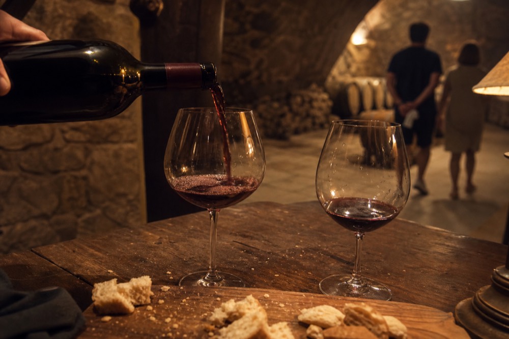 Red wine being poured into a tasting glass at a cellar table, no text, no logos, no people