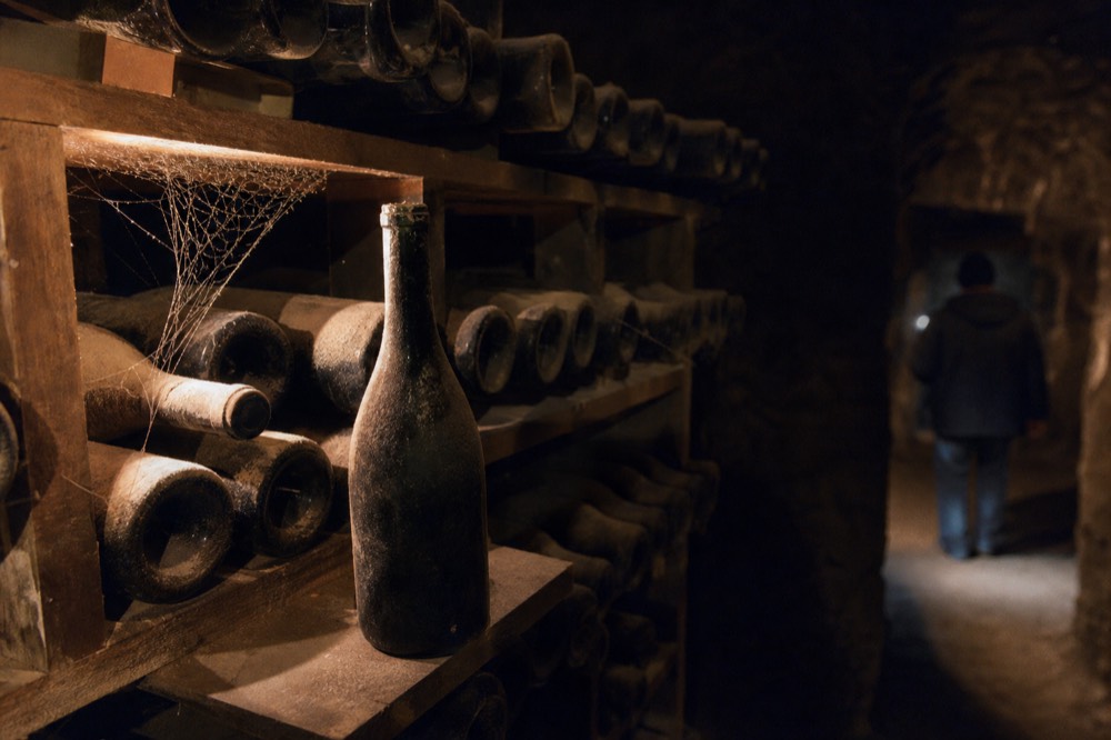 Aged Amarone bottles resting in a dark cellar, no text, no logos, no people
