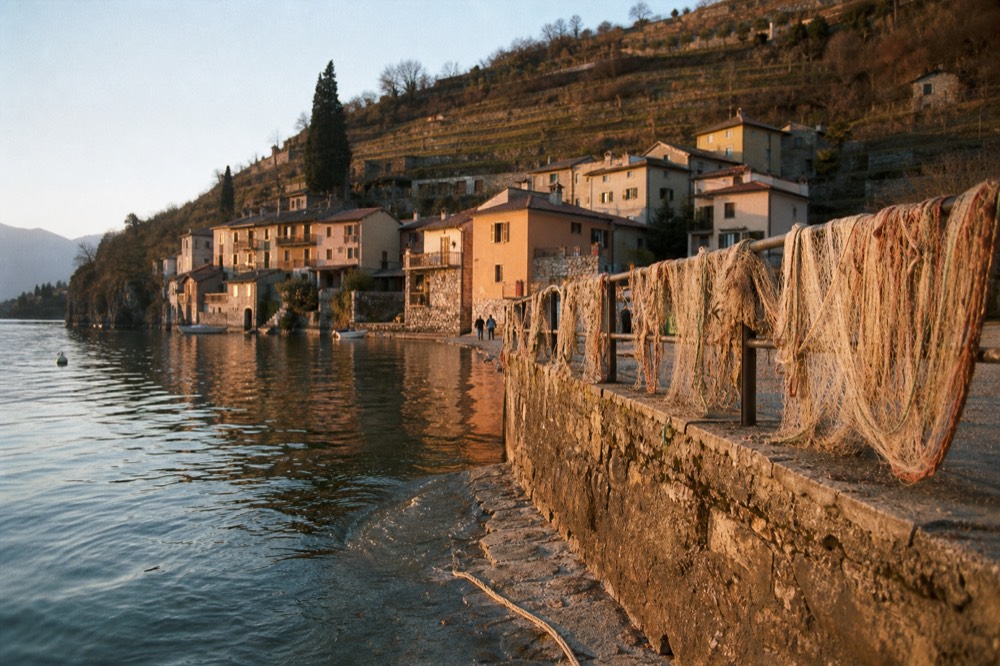 Village on the shore of Lake Garda with hills of vineyards behind, no text, no logos, no people