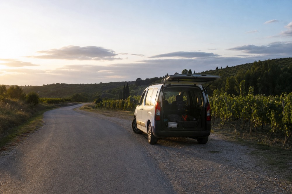 A small van parked on a hillside road beside vineyards in Valpolicella, no text, no logos, no people