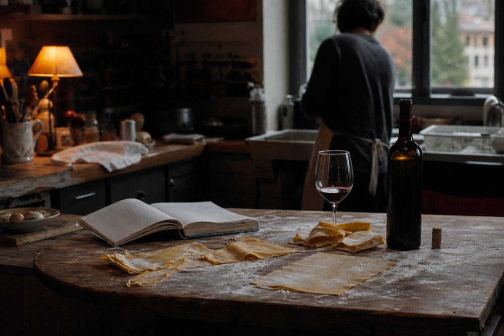 A rustic kitchen counter with fresh pasta, a bottle of Valpolicella, and a recipe book, no text, no logos, no people