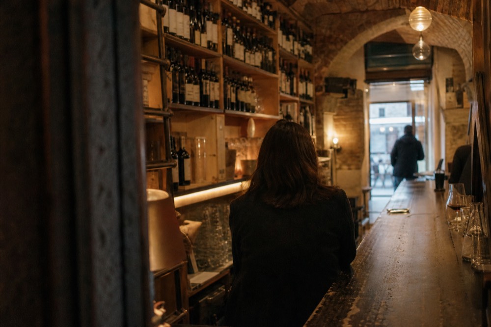 Wine bar interior with bottles racked to the ceiling near Piazza delle Erbe, no text, no logos, no people