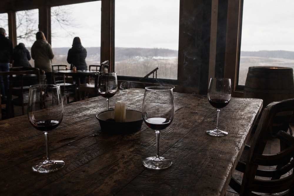 A rustic tasting room with glasses of red wine on a wooden table, no text, no logos, no people